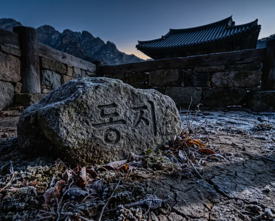 일 년 중 밤의 길이가 가장 길고 겨울의 정점에 달하는 동지 절기의 뜻을 담아, 인물을 완전히 배제하고 땅거미가 짙게 깔린 한겨울 얼어붙은 산길 고갯마루 선상에 긴 그림자가 드리워진 밤의 서사를 근접 촬영하고, 배경의 거대한 화강암 기둥 선상에 정교한 서체로 "동지" 한글 키워드가 입체적으로 박혀 있는 생태 화보 스타일의 극실사 이미지